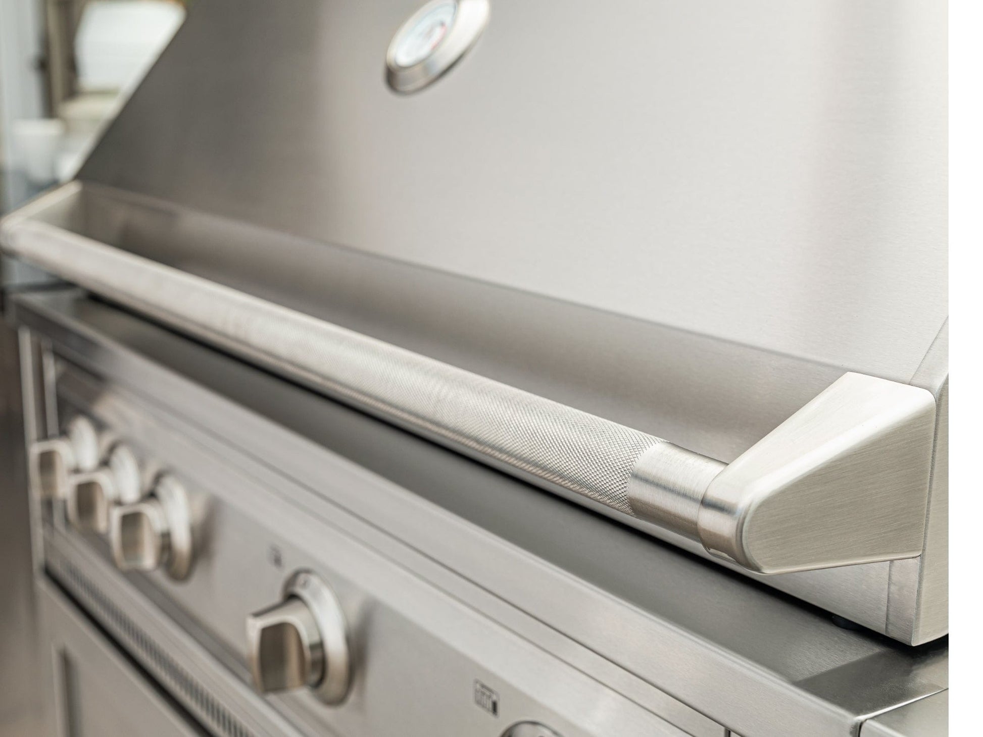 Stainless steel outdoor grill with closed lid, modular cabinets, and sleek finish for luxury outdoor kitchens.