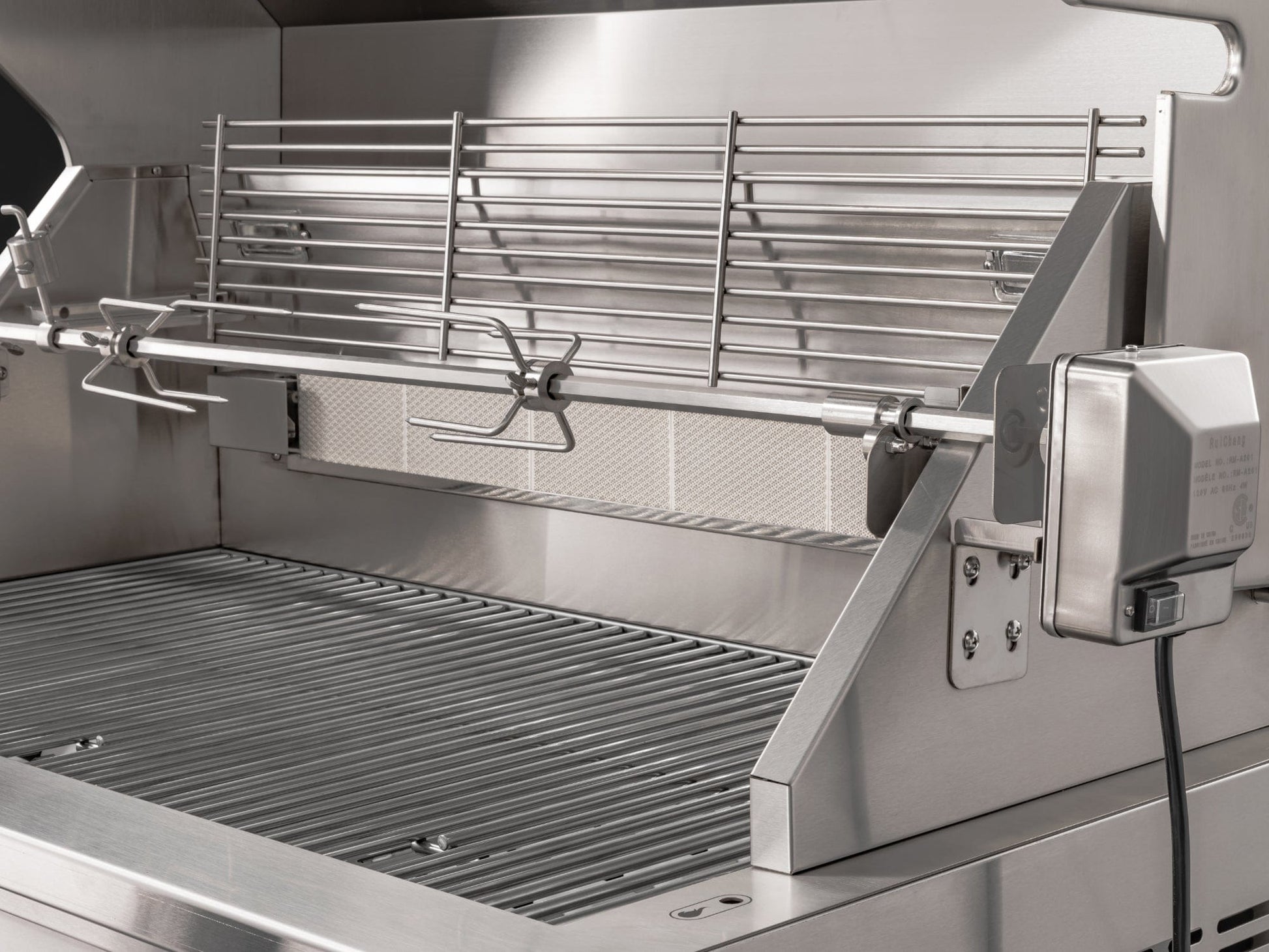 Premium stainless steel grill with rotisserie next to modular outdoor kitchen cabinets and sleek finish.