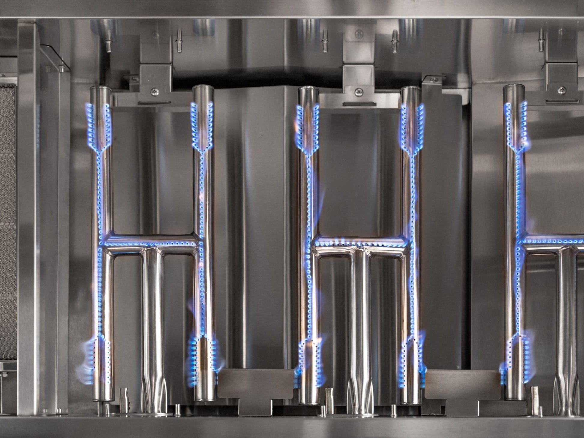 Premium stainless steel gas grill burners with blue flames in a sleek modular outdoor kitchen setup.
