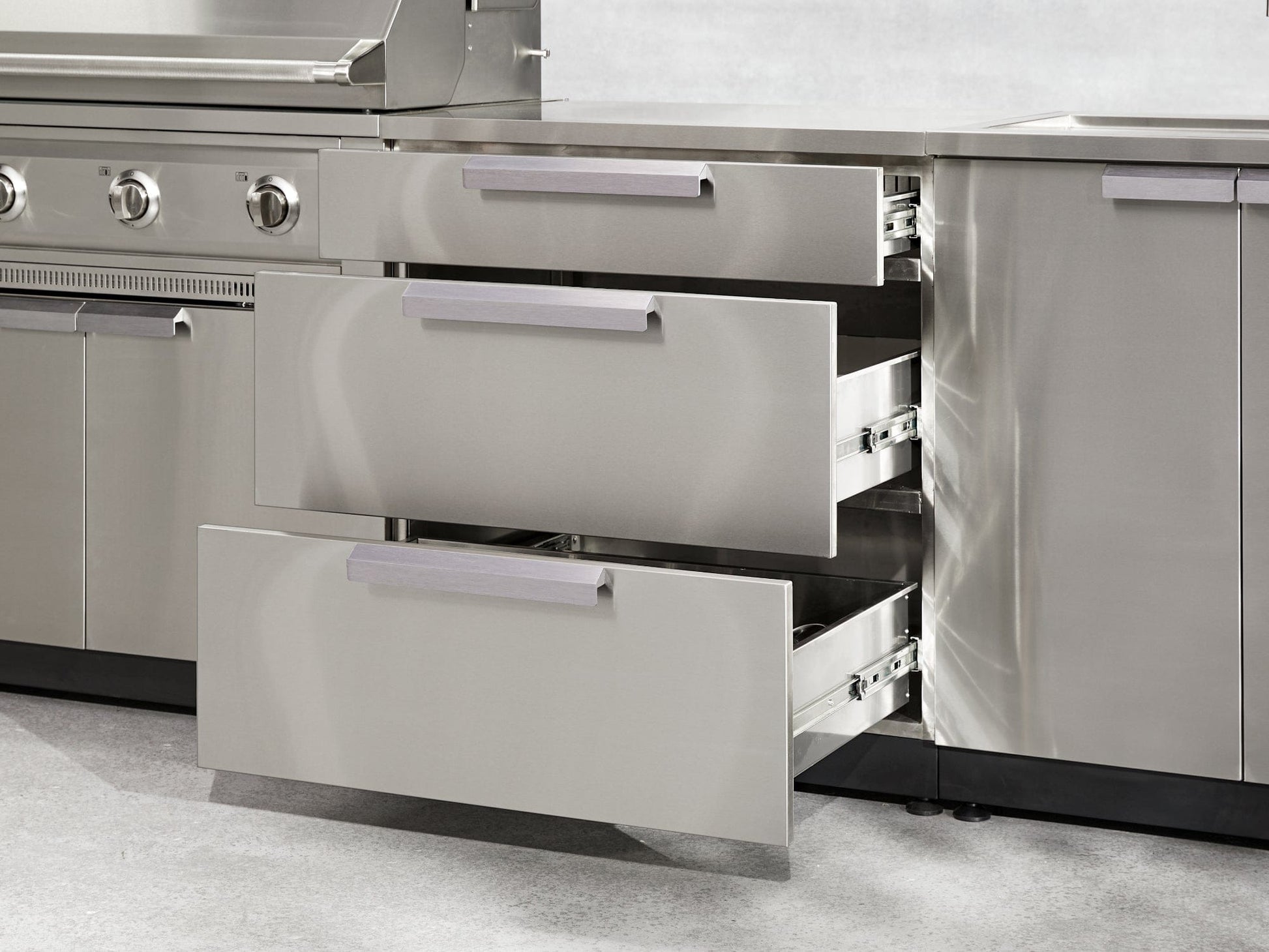 Stainless steel kitchen drawers open next to an outdoor grill and counter, ideal for premium backyard kitchens.