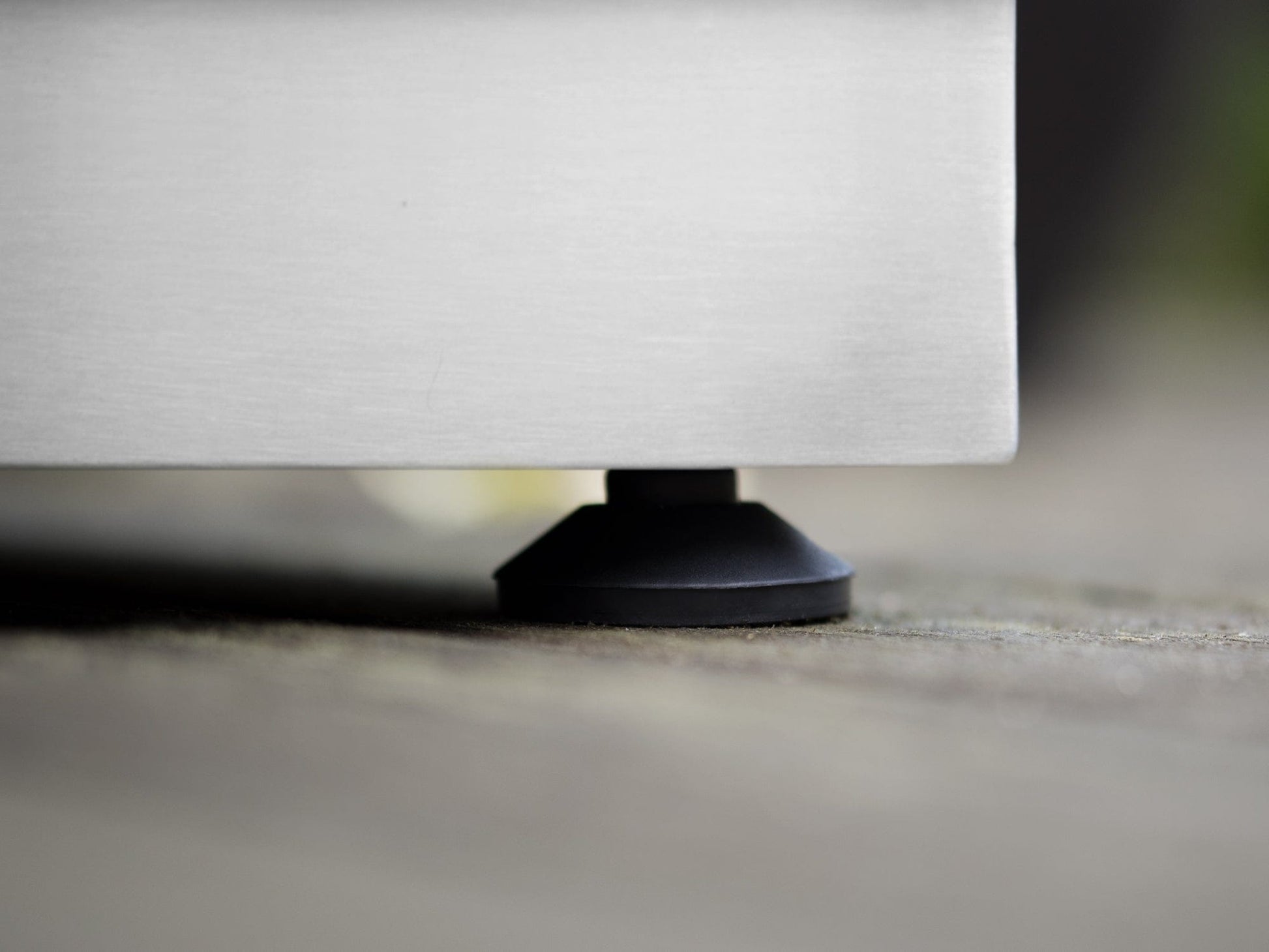 Black adjustable foot beneath stainless steel cabinets on wood floor, highlighting sturdy, premium outdoor design.
