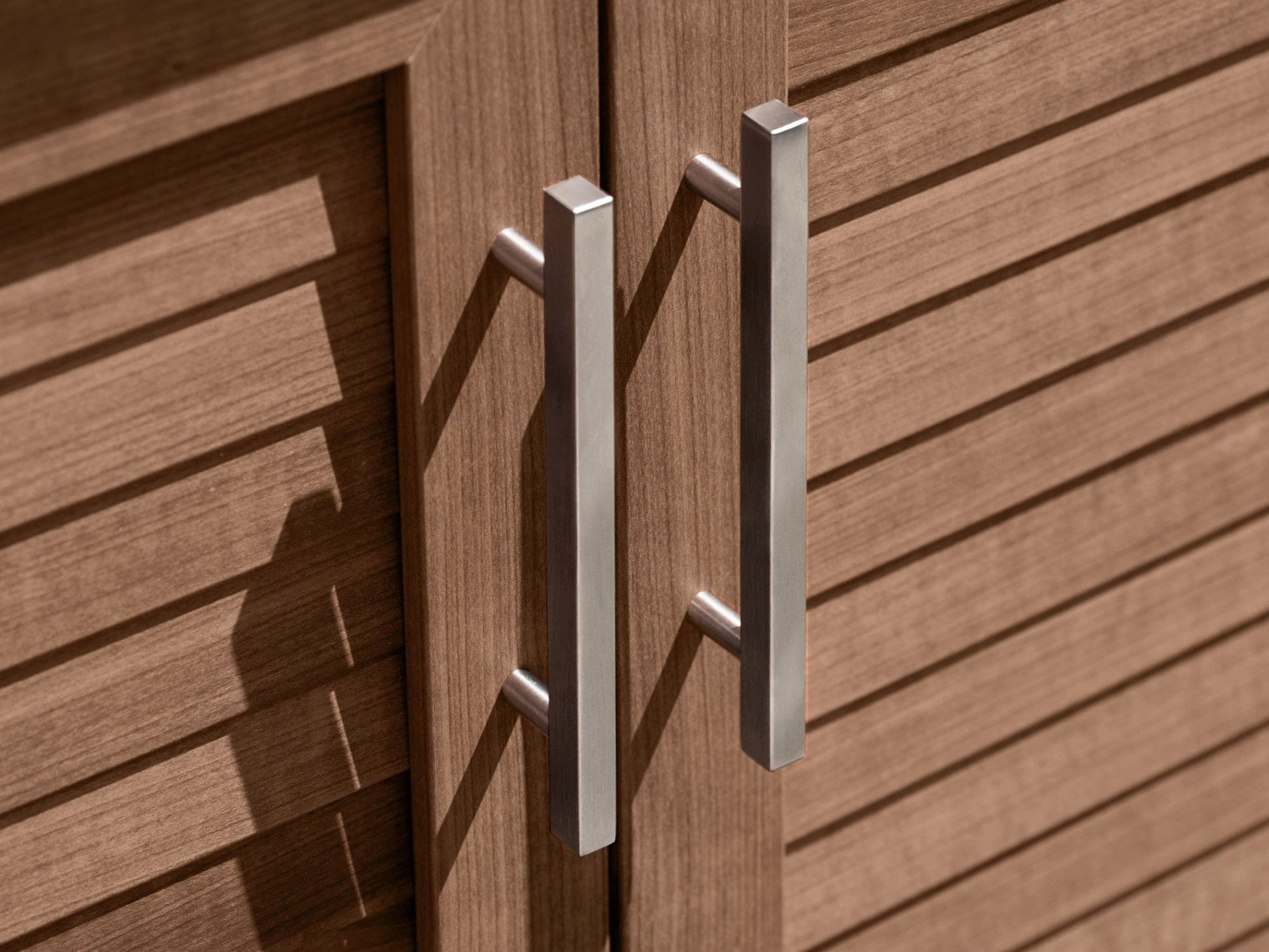 Brown outdoor kitchen cabinet doors with slatted design and dual vertical metal handles for a premium finish.