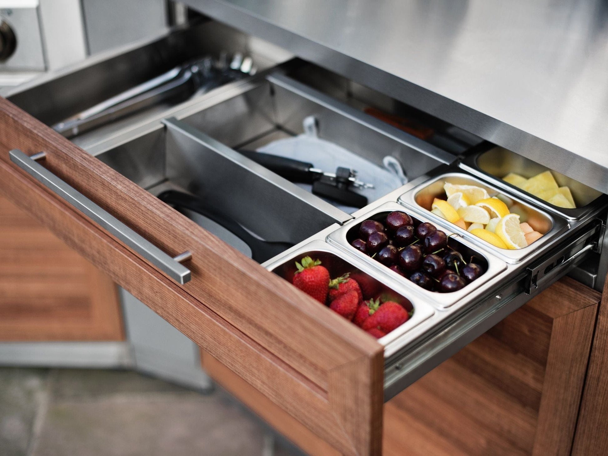 Outdoor kitchen drawer open, showing fruit trays; stainless steel finish adds luxury to your outdoor space.