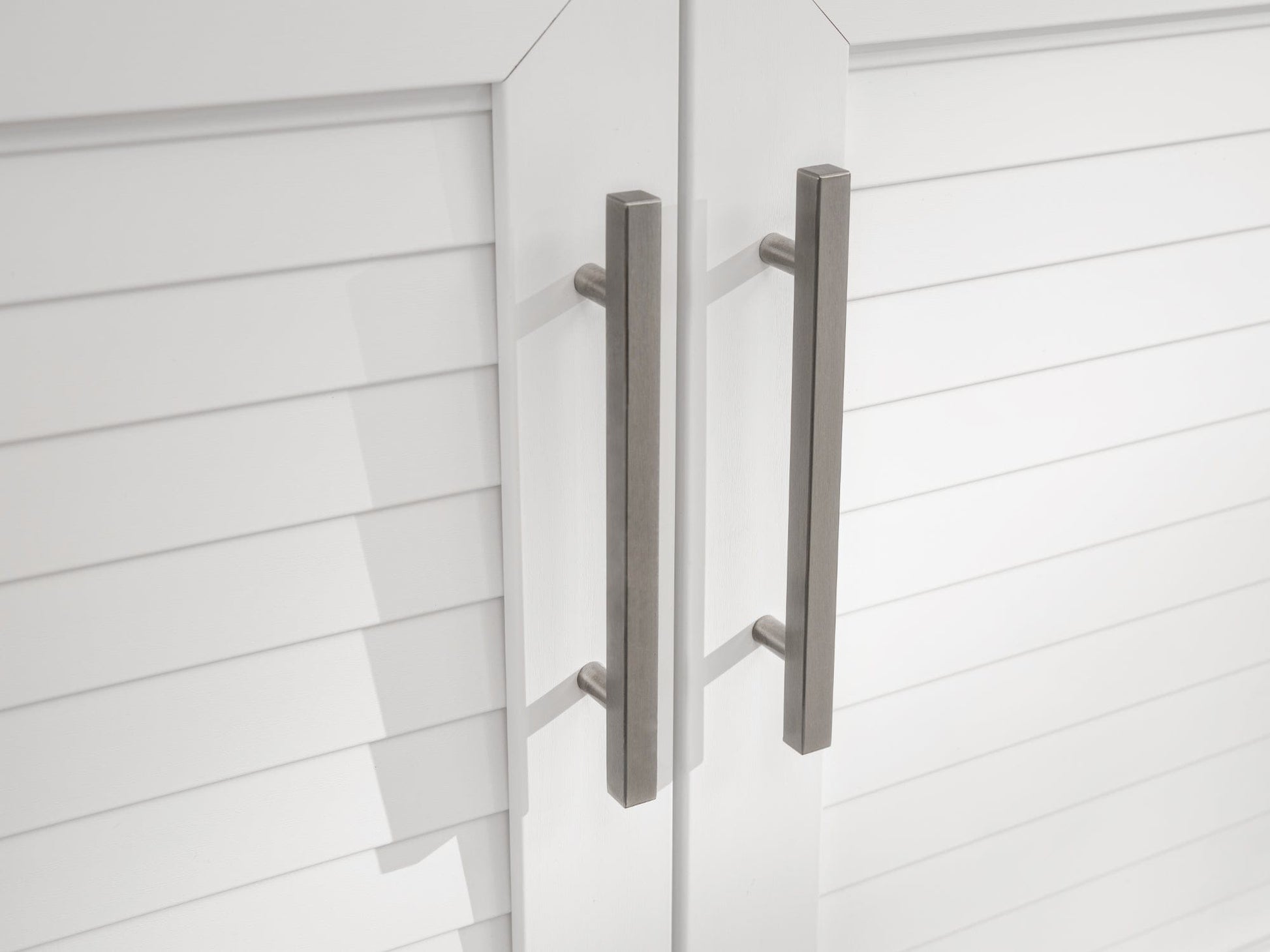 Sleek silver handles on white slatted doors, perfect for upscale modular outdoor kitchens with a durable finish.