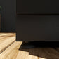 Premium black stainless steel outdoor cabinets on wood floor, sleek finish, with plant accent in background.