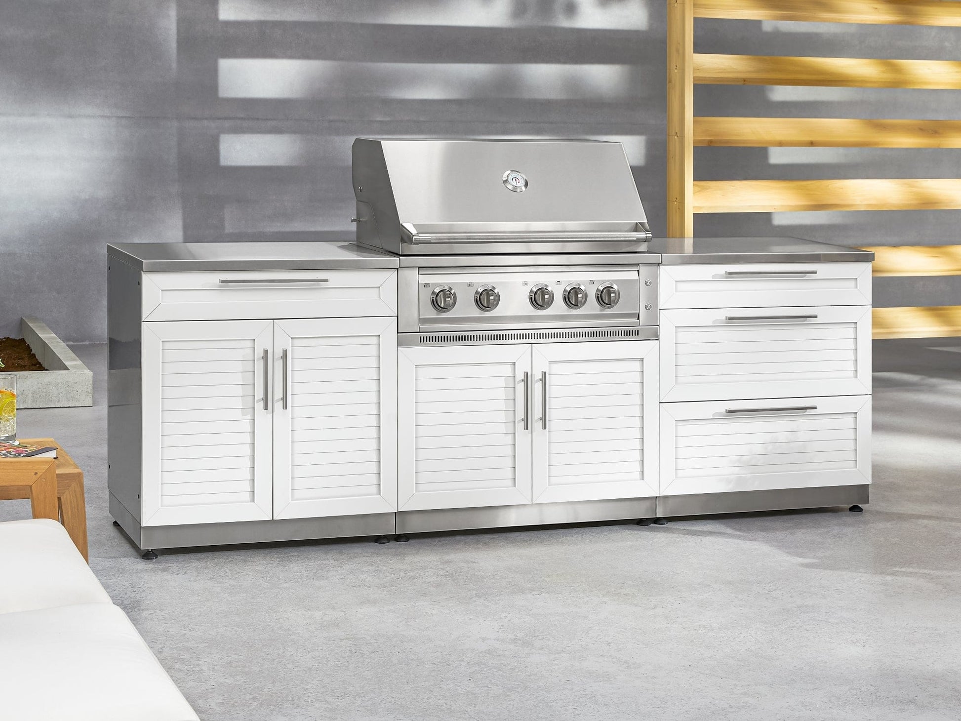 Premium outdoor kitchen with NewAge cabinets, built-in stainless grill, side burner, and sink on concrete patio.